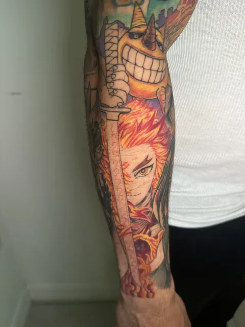 Anime forearm tattoo of a flame-haired swordsman under a grinning horned figure