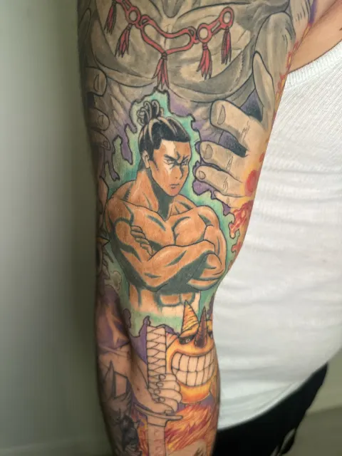 Anime upper-arm tattoo of a bare-chested samurai standing with crossed arms in green fire