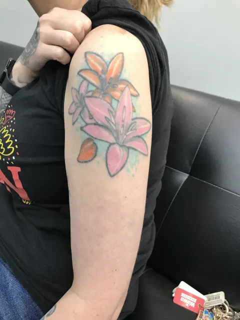 Tatuaje de lirios rosados en el hombro antes del cover up