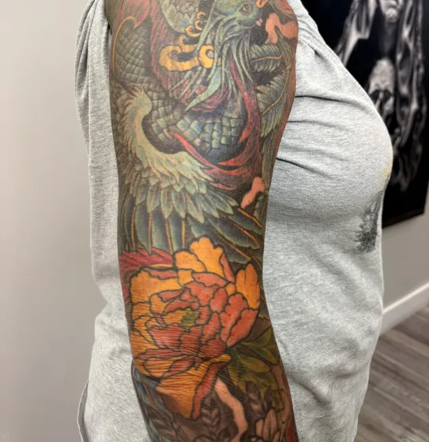 Healed full color sleeve of a phoenix over orange peonies and dark florals, photographed after healing