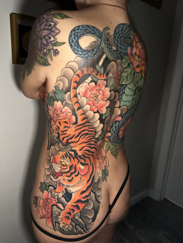 Neo-Oriental tattoo of a tiger and serpent woven through waves and flowers